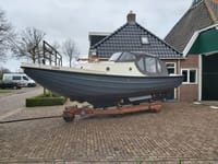 Een tweekleurige boot met de naam "HISSE" op de boeg staat op een trailer voor een huis. — Langenberg Borndiepvlet 8.00