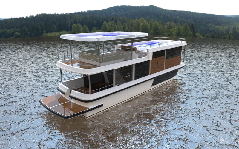 Een witte woonboot met twee verdiepingen en een houten achterdek, drijvend op water met een beboste heuvel op de achtergrond.