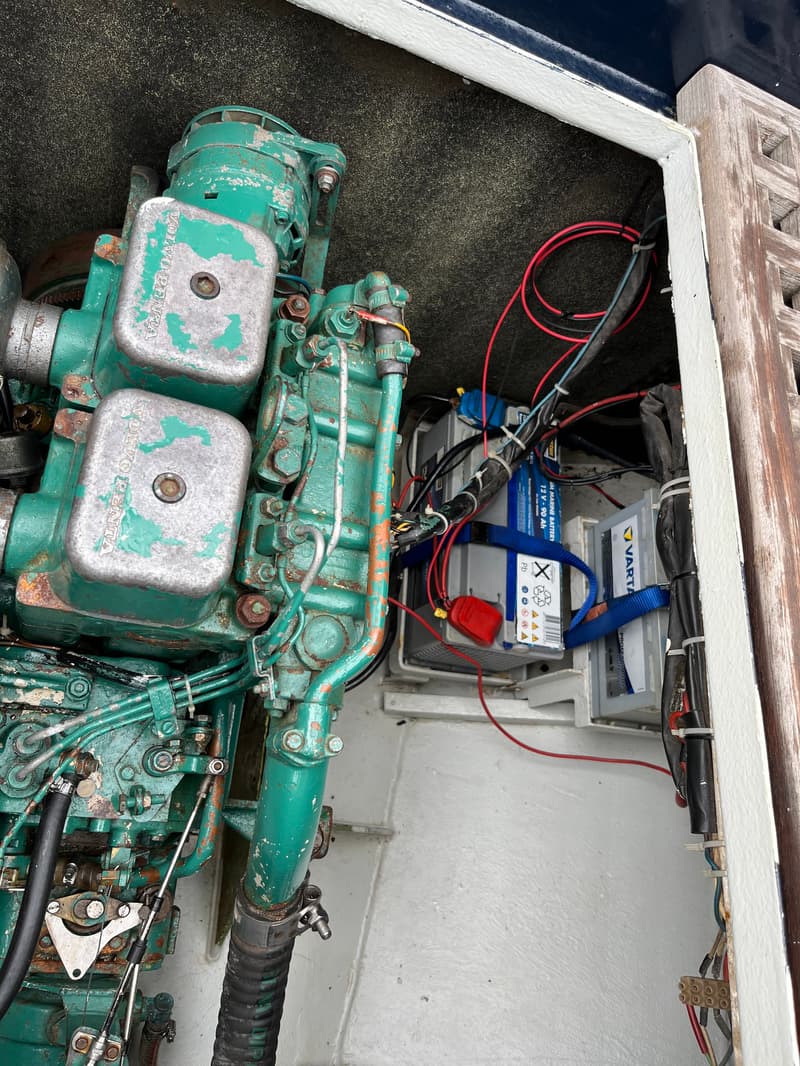 Een groene Volvo Penta motor en twee Varta accu's zijn zichtbaar in een motorruimte.