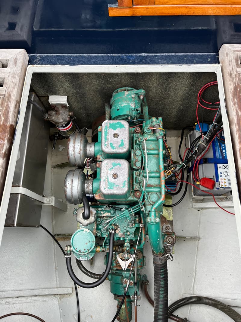 Een close-up van een groene scheepsmotor met de tekst "VOLVO PENTA" en een accu in een motorruimte.