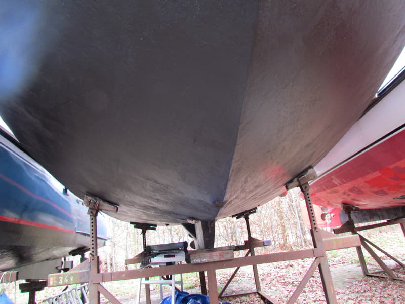 De onderkant van een donkere boot, ondersteund door een metalen frame, met aan weerszijden delen van andere boten.