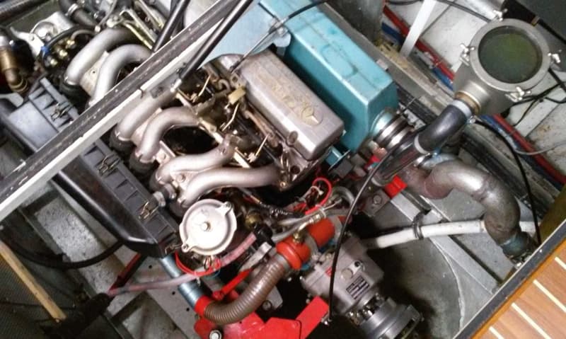 Een close-up van een scheepsmotor met diverse leidingen, slangen en een Mercedes-Benz logo op de motor.