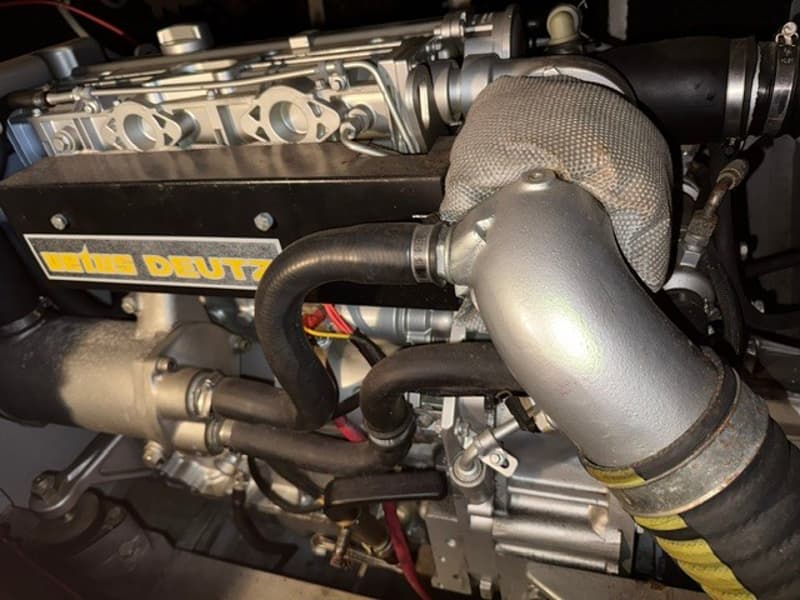 Een close-up van een scheepsmotor met de tekst "DEUS DEUTZ" op een zwarte afdekplaat.
