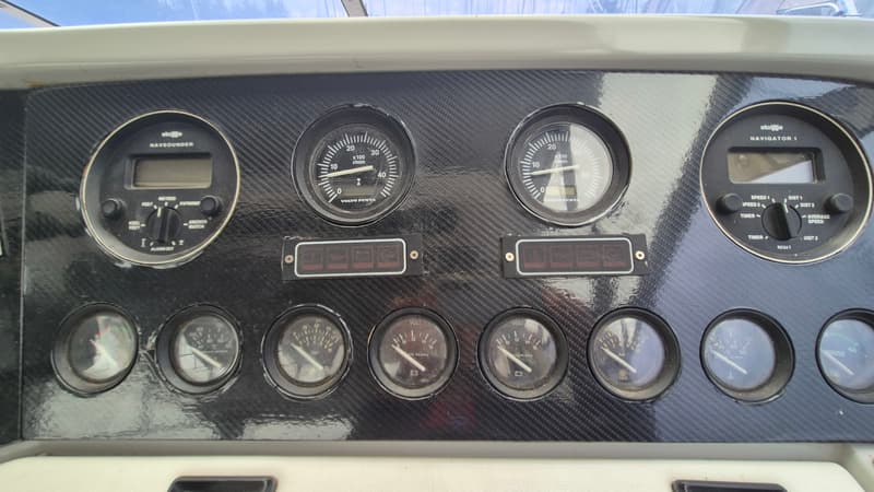 Een dashboard van een boot met diverse meters, waaronder een dieptemeter, toerentellers en spanningsmeters.