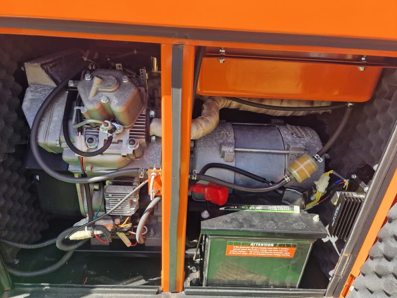 Een detailfoto van een motorcompartiment met een motor, een accu en diverse kabels en slangen.