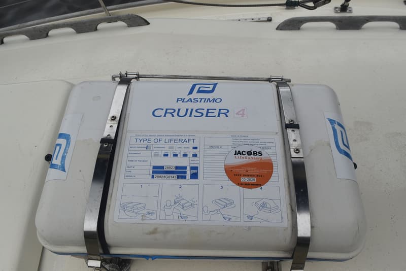 Een witte reddingsvlotcontainer van Plastimo Cruiser 4 met instructies en een Jacobs LifeSaving sticker.