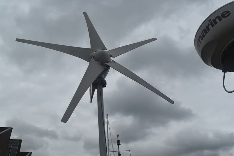 Een windgenerator met vijf bladen en een Raymarine radar op een boot, onder een bewolkte hemel. — Frans Maas Raider 35