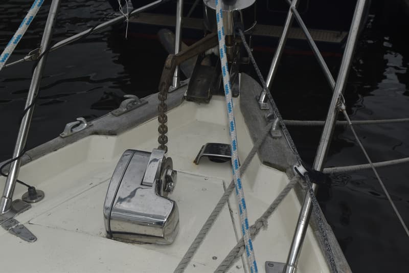 Een close-up van de boeg van een zeilboot met een ankerlier, ketting en diverse lijnen en beslag. — Frans Maas Raider 35