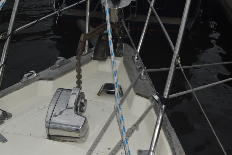 De boeg van een zeilboot met een ankerlier, ankerketting, touwen en reling is zichtbaar. — Frans Maas Raider 35