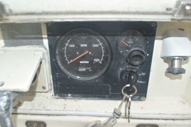Een close-up van een dashboard met een toerenteller, een voltmeter en een contactsleutel met sleutelbos.
