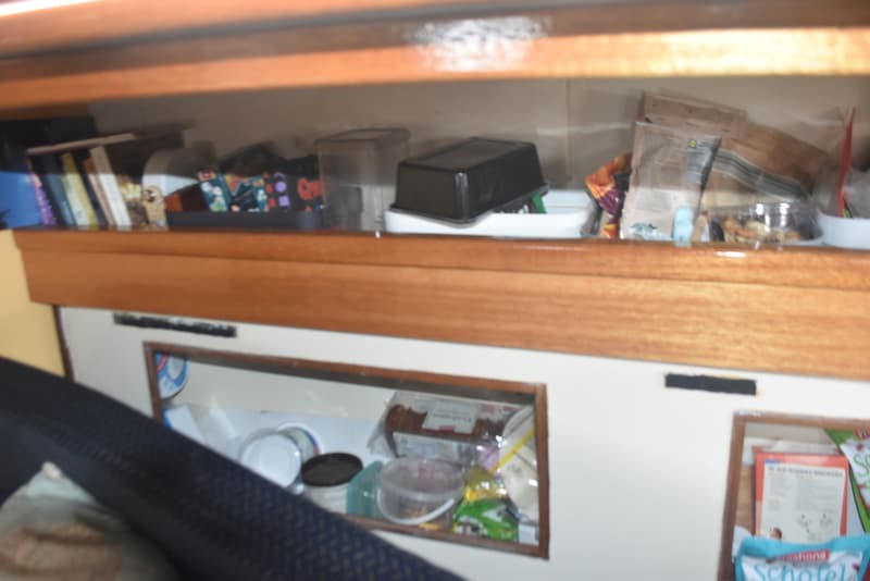 Een interieur van een boot met houten planken, boeken, opbergbakken en verpakte etenswaren. — Frans Maas Raider 35
