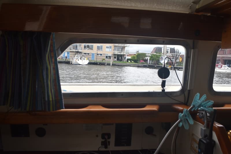 De foto toont het interieur van een boot met uitzicht op een kanaal met huizen en andere boten. — Frans Maas Raider 35