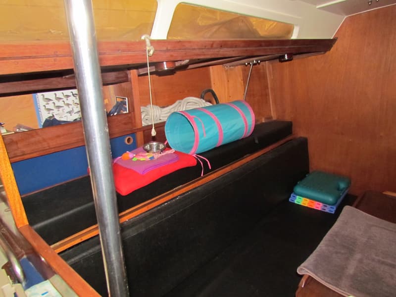 De foto toont een interieur van een boot met houten wanden, zwarte banken en diverse voorwerpen. — Waarschip 900 +
