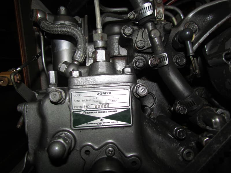Een detailopname van een Yanmar dieselmotor met een naamplaatje waarop "2GM20" en "16 H.P. 3400 rpm" staat.