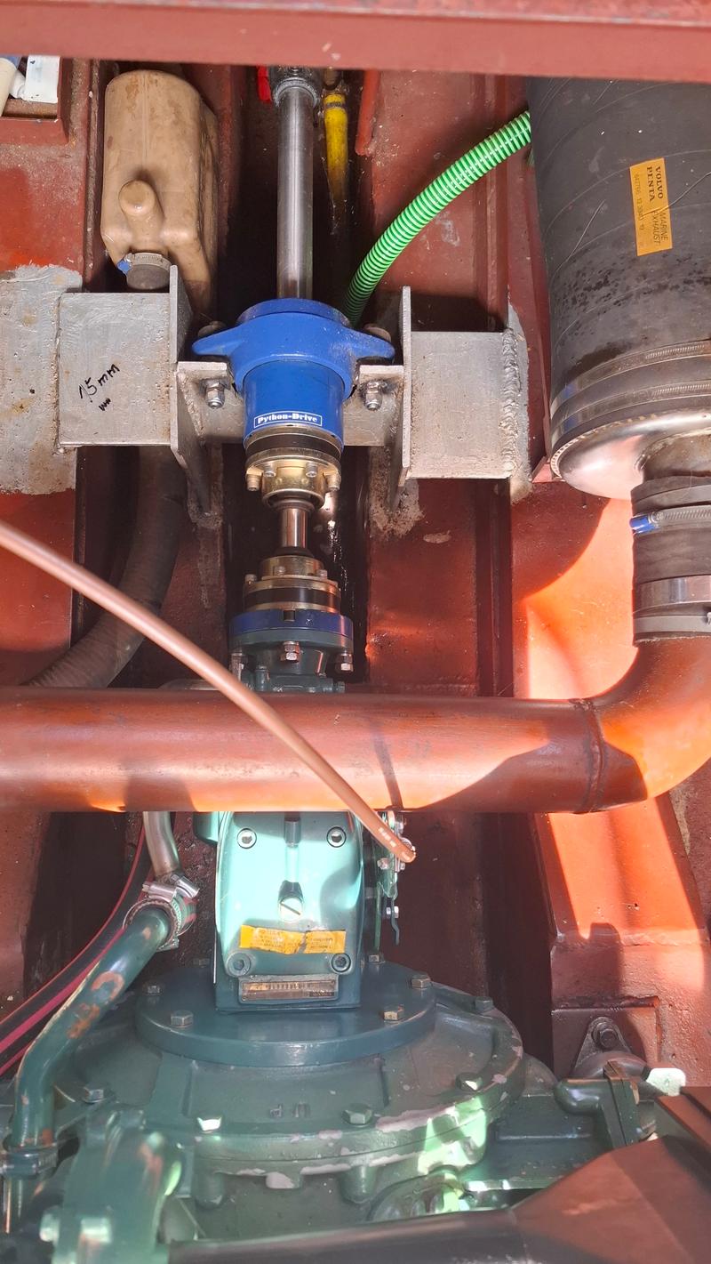 De foto toont een deel van een scheepsmotor met een Python-Drive koppeling, diverse leidingen en een Volvo Penta uitlaat.
