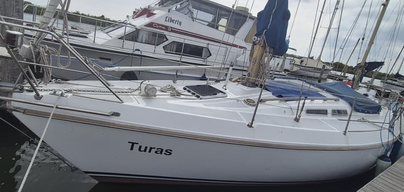 Een witte zeilboot met de naam "Turas" ligt afgemeerd aan een steiger, met een motorjacht erachter. — Contest 36 Ketch