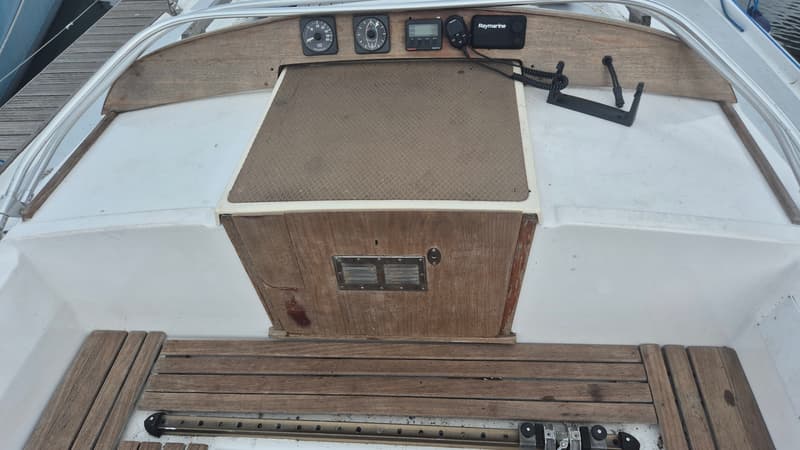 Een bovenaanzicht van een bootdek met houten panelen, instrumenten en een Raymarine-apparaat.