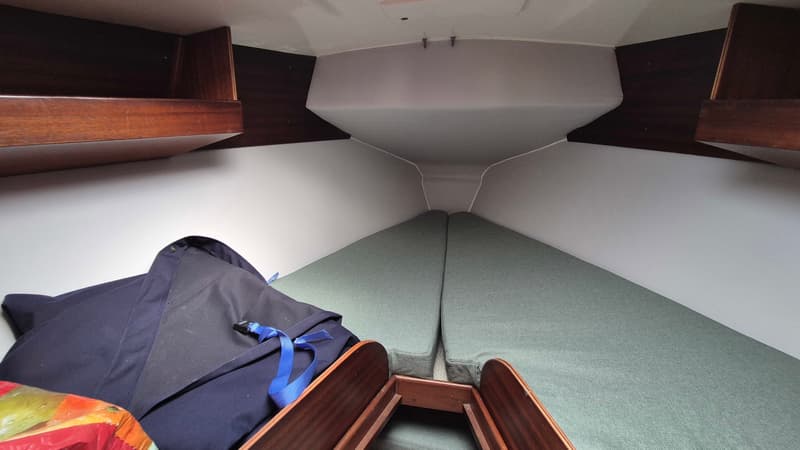De foto toont het interieur van een kajuit met twee groene kussens en houten planken aan de zijkanten. — Contest 36 Ketch