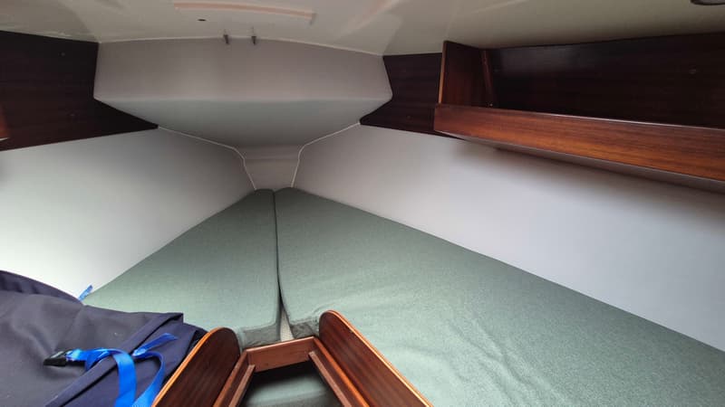 De foto toont de kajuit van een boot met twee groene kussens die een V-vormig bed vormen. — Contest 36 Ketch
