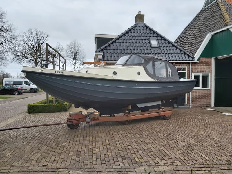 Een tweekleurige boot met de naam "HISSE" op de boeg staat op een trailer voor een huis. — Langenberg Borndiepvlet 8.00