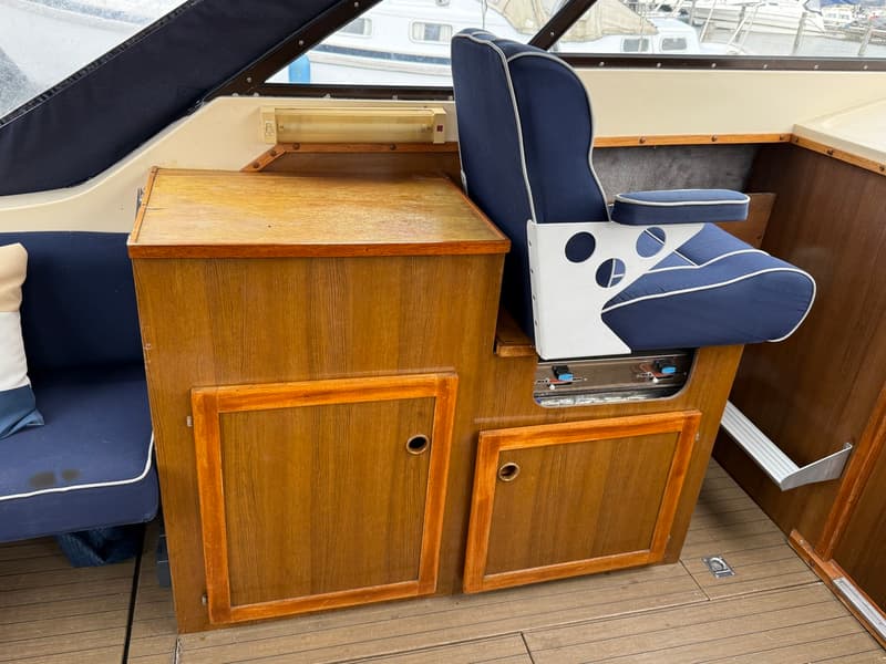 Een blauwe bootstoel met witte biezen en een houten kastje met twee deurtjes en een kookplaatje.