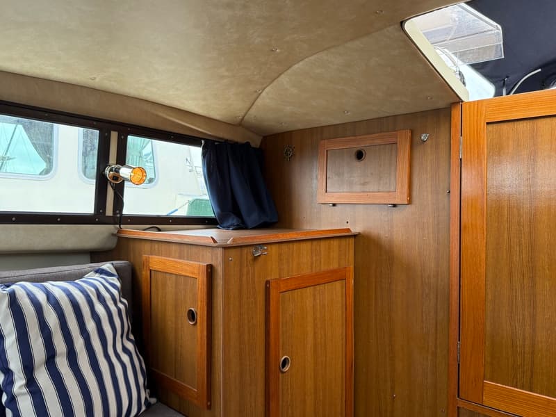 De foto toont het interieur van een kajuit met houten wanden, een gestoffeerd plafond en een gestreepte kussen. — Joda 7500