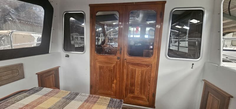 Een interieur van een boot met een houten dubbele deur, ramen en een tafel met een geruit tafelkleed. — Bach 1050 OK