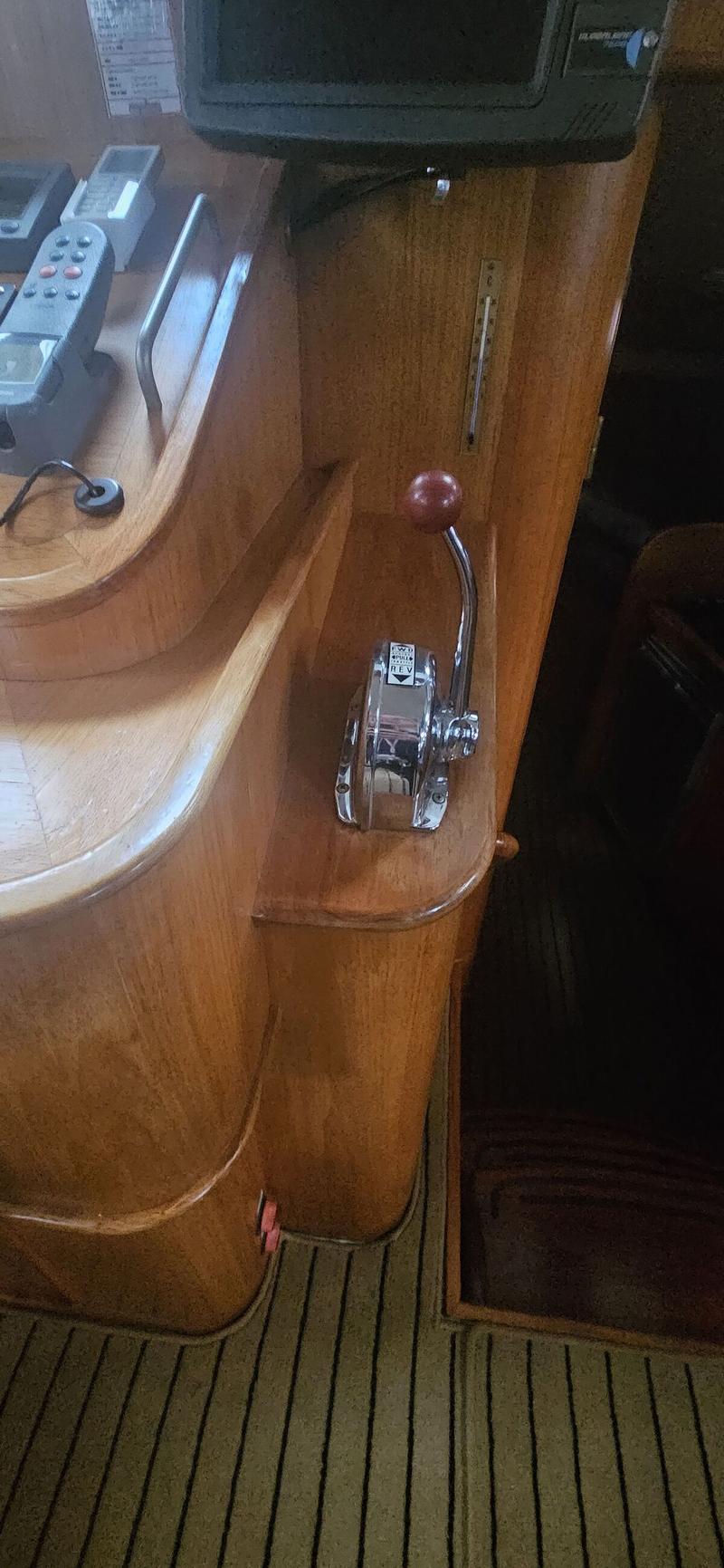 Een close-up van een houten interieur met een chromen gashendel met rode knop en een thermometer.
