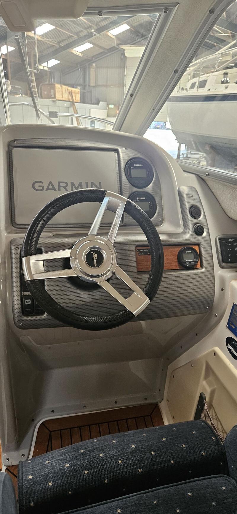 De foto toont het stuur van een boot met een Garmin-scherm, Yamaha-meters en een houten vloer. — Yamarin 68C