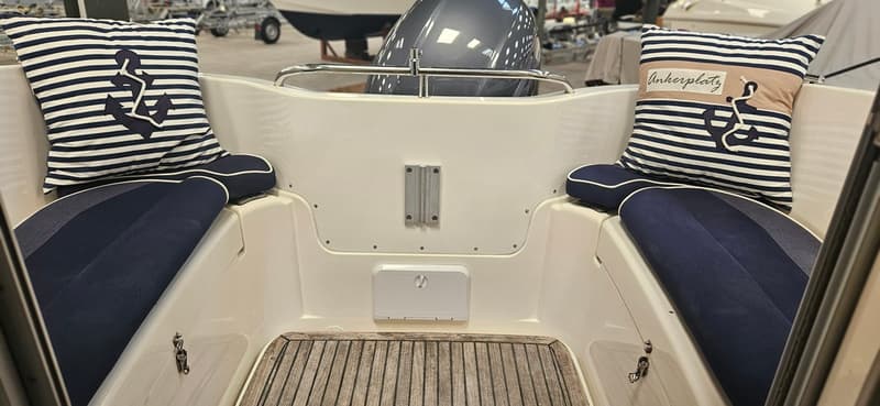 De foto toont het achterdek van een boot met twee blauw-wit gestreepte kussens en donkerblauwe zitkussens. — Yamarin 68C