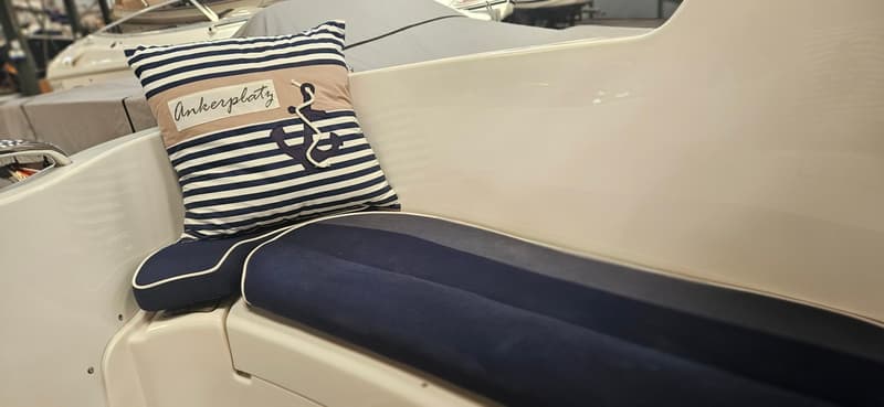 Een gestreept kussen met een anker en de tekst "Ankerplatz" ligt op een blauw zitkussen in een boot. — Yamarin 68C