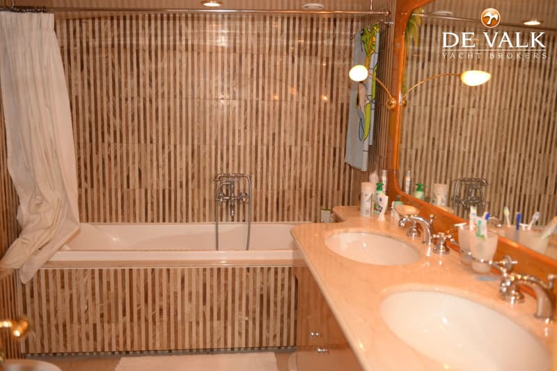 Een badkamer met een badkuip, twee wastafels, een spiegel en een douchegordijn.