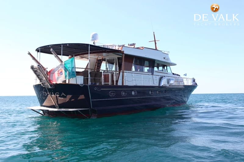 Een donkerblauwe motorboot met een witte opbouw en de naam "UNICA" op de spiegel ligt op het water. — Baglietto Maiorca