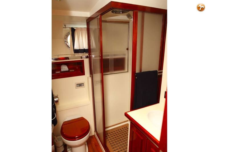 Een badkamer met een toilet, een douchecabine en een wastafelmeubel met een witte wasbak.