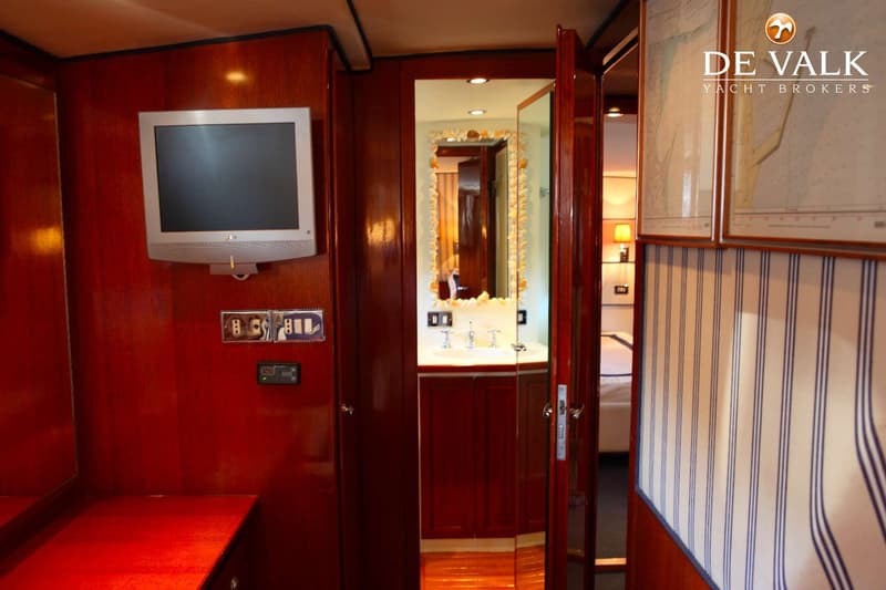 Een interieur van een boot met een flatscreen-tv, een badkamer met spiegel en een slaapkamer met gestreepte wandbekleding.