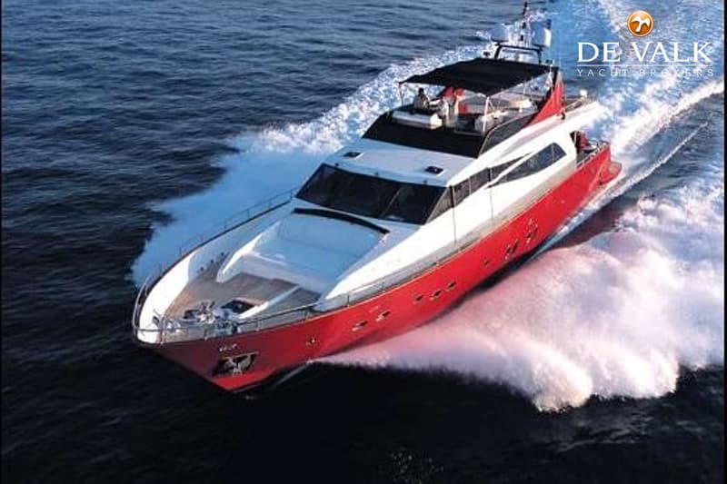 Een rode en witte motorjacht vaart over het water, met een spoor van schuim achterlatend.