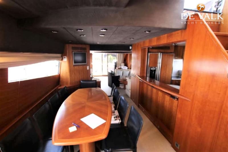 Een interieur van een jacht met een houten tafel, zwarte stoelen, een bank, een televisie en een trap. — Couach 2800 Fly