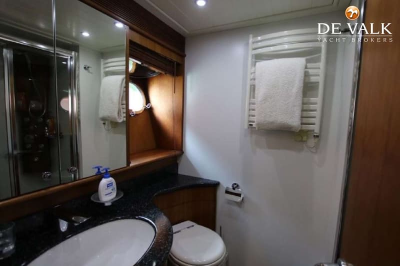 Een badkamer met een wastafel, spiegel, douchecabine, toilet, handdoekradiator en patrijspoort.