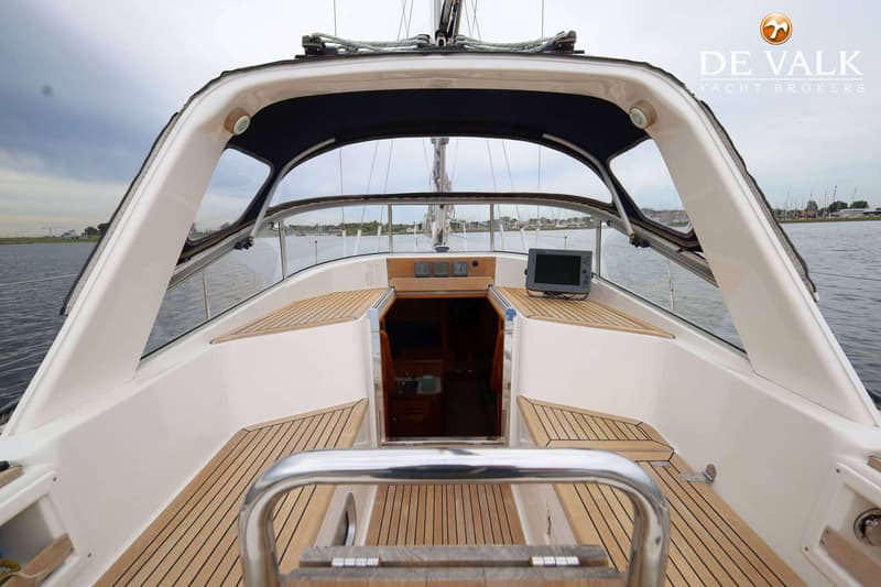 De foto toont het dek van een zeilboot met een houten vloer, een kajuitingang en navigatieapparatuur. — Malo 37