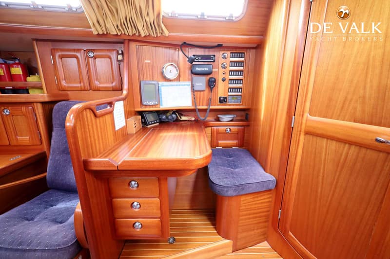Een houten interieur met een navigatietafel, stoel en bankje, diverse instrumenten en een schakelpaneel.
