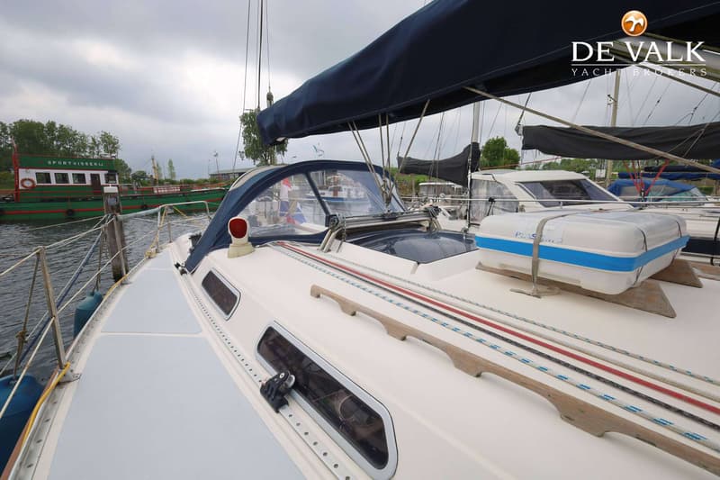 Een zeilboot ligt aangemeerd met een blauwe buiskap en een reddingsvlot op het dek. — Hanse 401