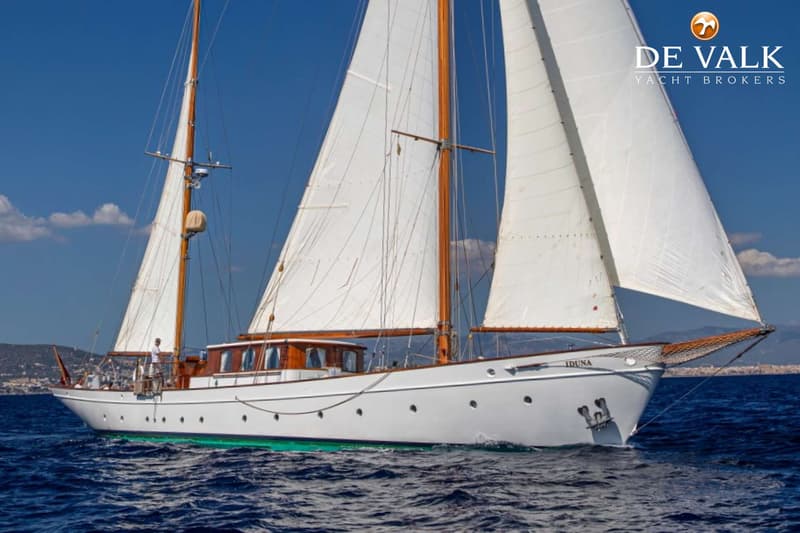Een witte zeilboot met houten masten en gieken vaart op een blauwe zee onder een heldere hemel. — Feadship Ketch