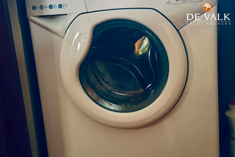 Een witte wasmachine met een ronde deur en een bedieningspaneel aan de bovenzijde.
