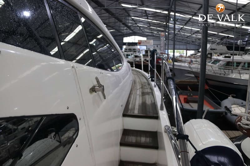 Een witte boot met houten dek en ramen met regendruppels, binnen in een loods met andere boten. — Azimut 68 Plus