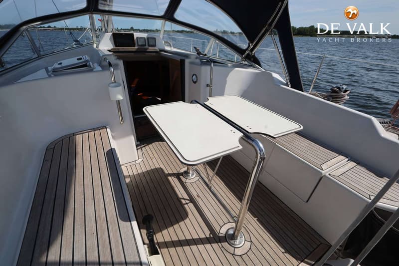 De foto toont de kuip van een zeilboot met een houten dek, een inklapbare tafel en zitbanken. — Dehler 41 Cruising