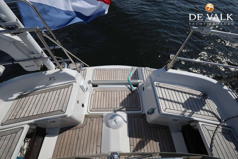 De foto toont het achterdek van een boot met een houten vloer, een Nederlandse vlag en een reddingsboei. — Dehler 41 Cruising