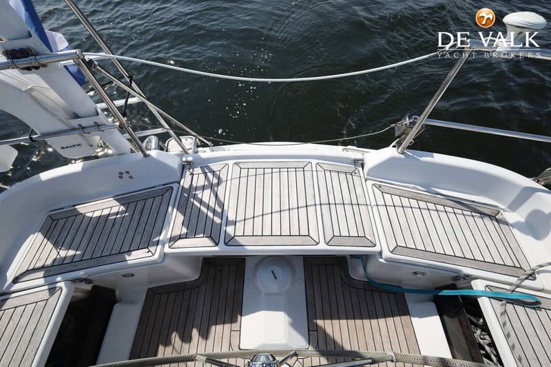 Het dek van een boot met houten latten, een reddingsboei met "BALTIC" erop en water op de achtergrond. — Dehler 41 Cruising