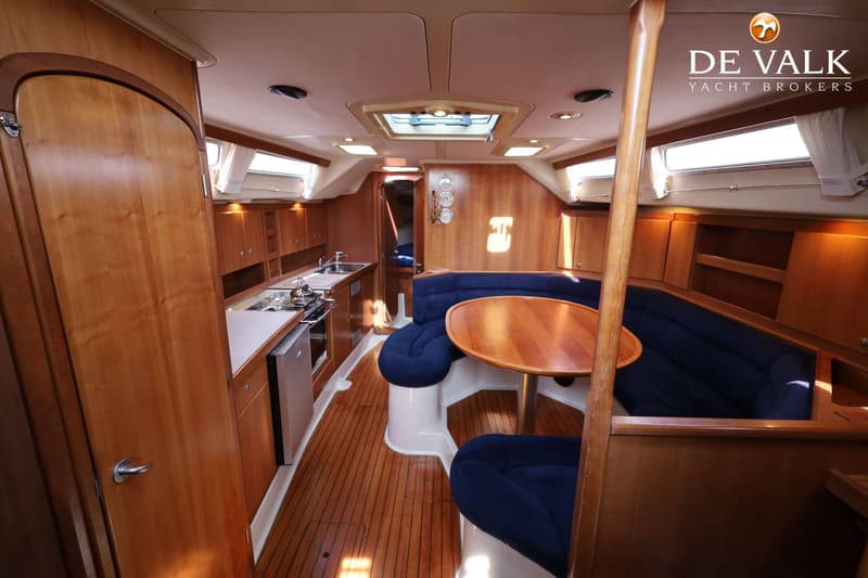 De foto toont een houten interieur van een boot met een kombuis, zithoek en een tafel. — Dehler 41 Cruising