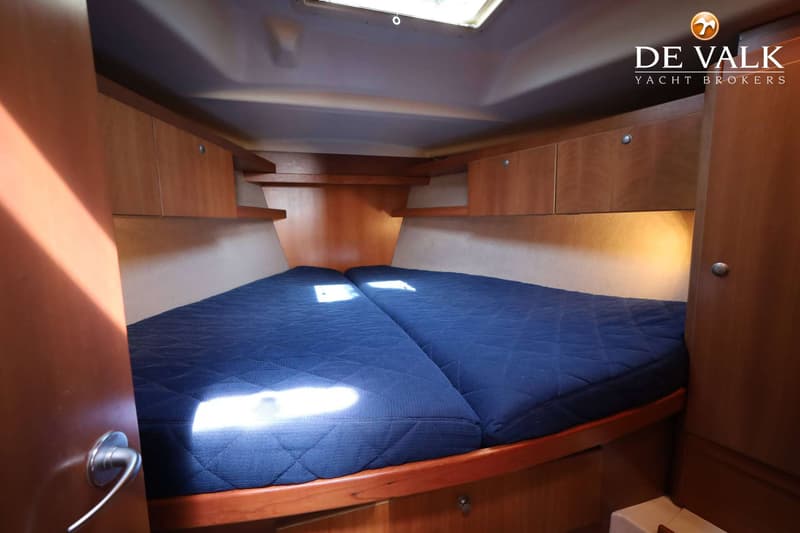 De foto toont een kajuit met twee blauwe matrassen, houten kasten en planken, en een dakluik. — Dehler 41 Cruising