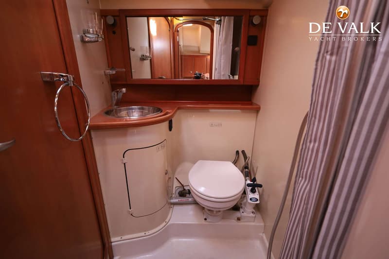 Een badkamer met een toilet, wastafel en spiegel, met een gestreepte douchegordijn aan de rechterkant.